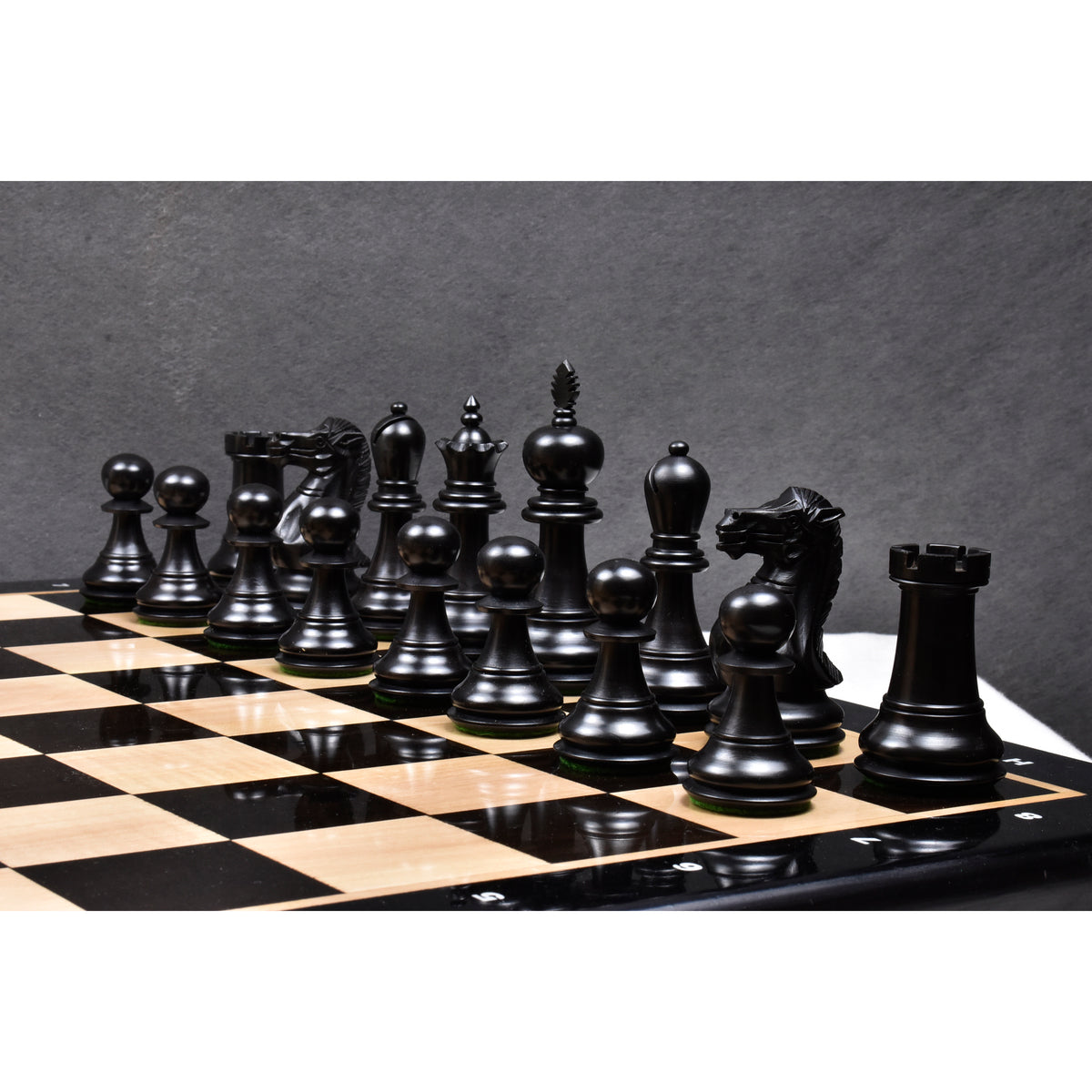 A set of dark ebonised boxwood executive staunton pieces placed on a board.