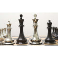 Polished silver and dark grey brass metal kings and queens lined up on a checkered board.