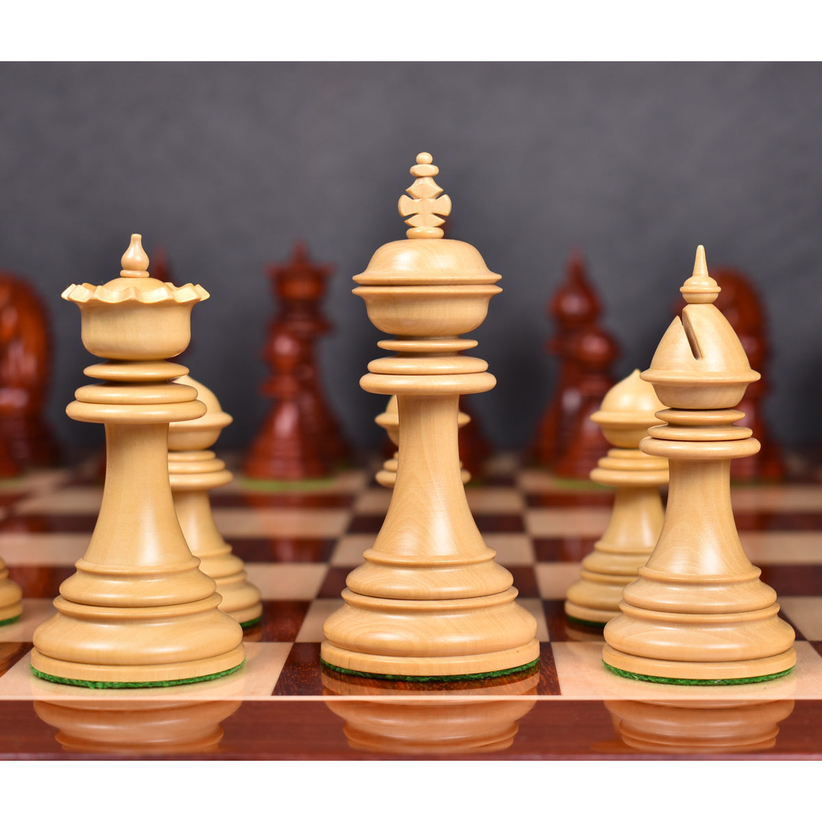 Ground-level view of natural boxwood Dragon Staunton King, Queen, and Bishop pieces on a wood chessboard.