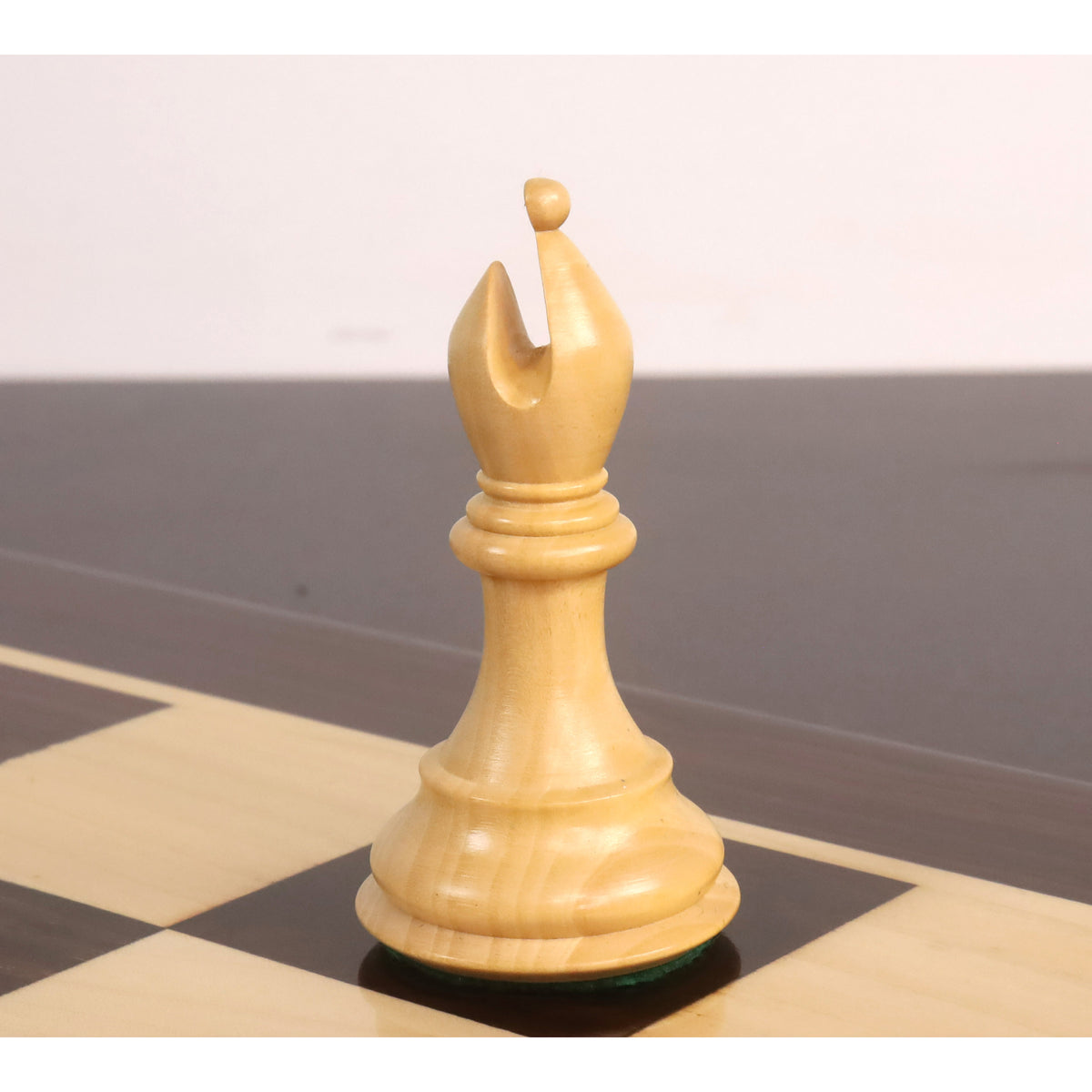 Light boxwood bishop from the 4-inch sleek Staunton luxury chess set positioned on a checkered board.