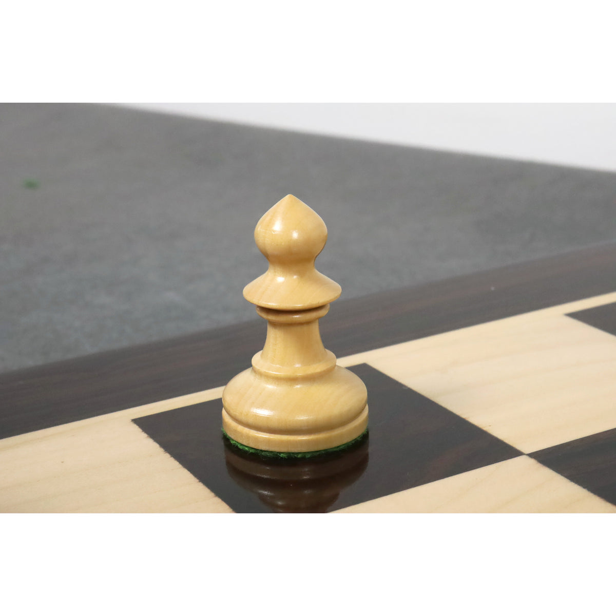 A light boxwood pawn from the reproduced Pinney Staunton series positioned on a chessboard.