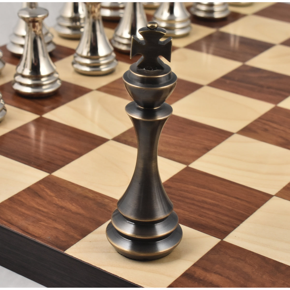 High-end antique brass metal luxury chess king piece showing intricate cross finial detail on a board.