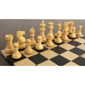 Natural boxwood Staunton chess pieces arranged on a black and tan checkered chess board.