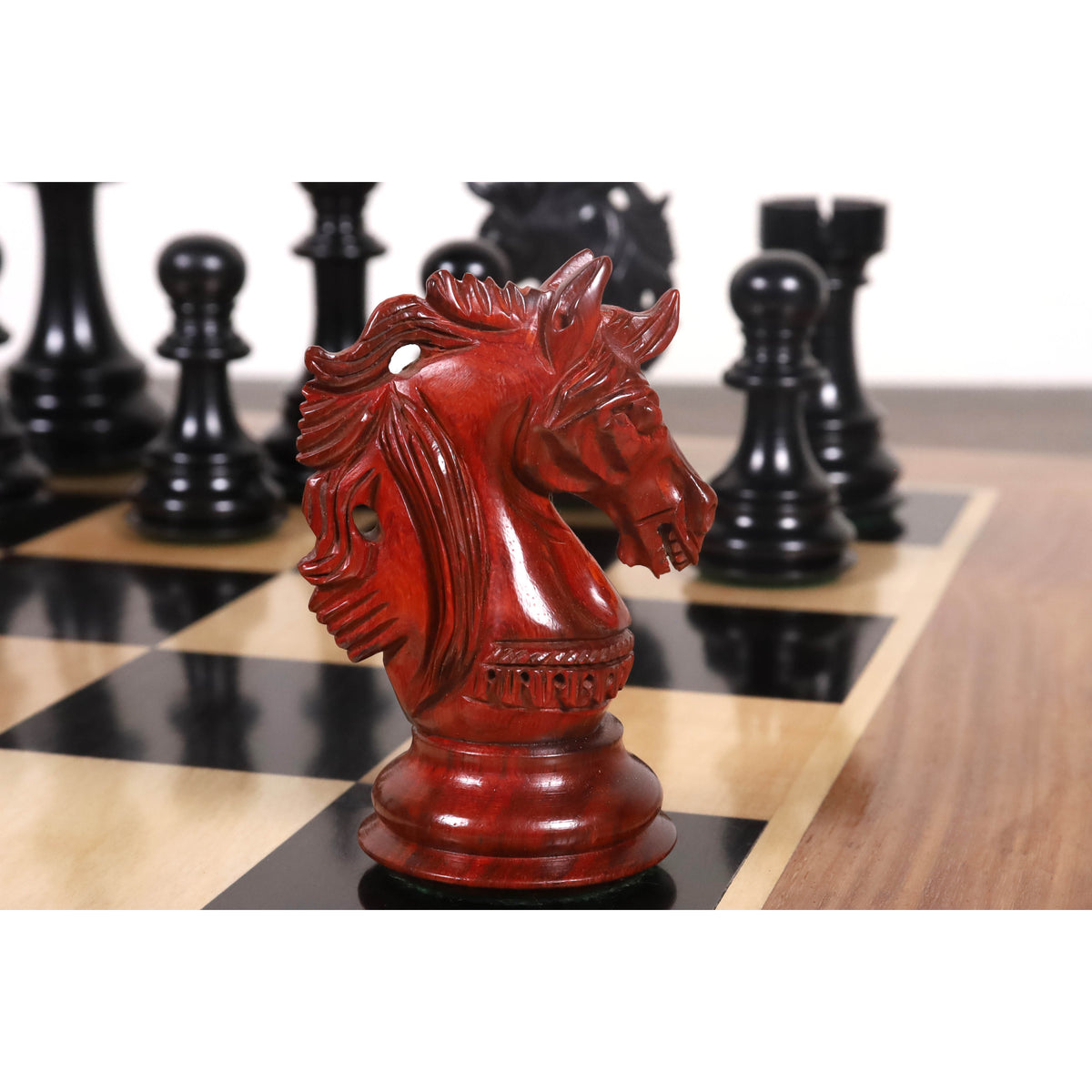 Close-up perspective of a hand-carved Bud Rosewood knight placed on a contrasting black and light wood square.