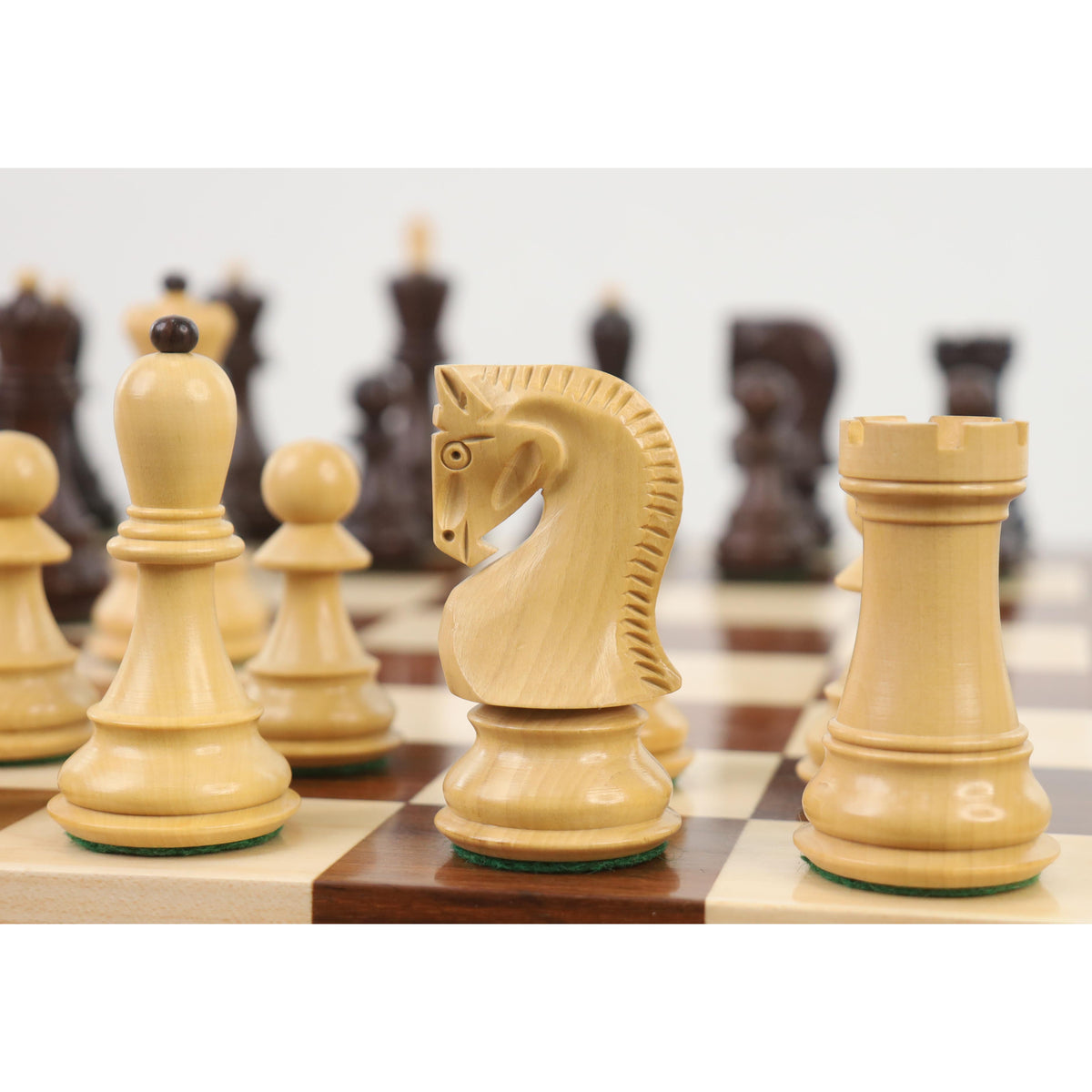 Handcrafted boxwood knight and rook pieces arranged on an eDensity wooden chessboard.