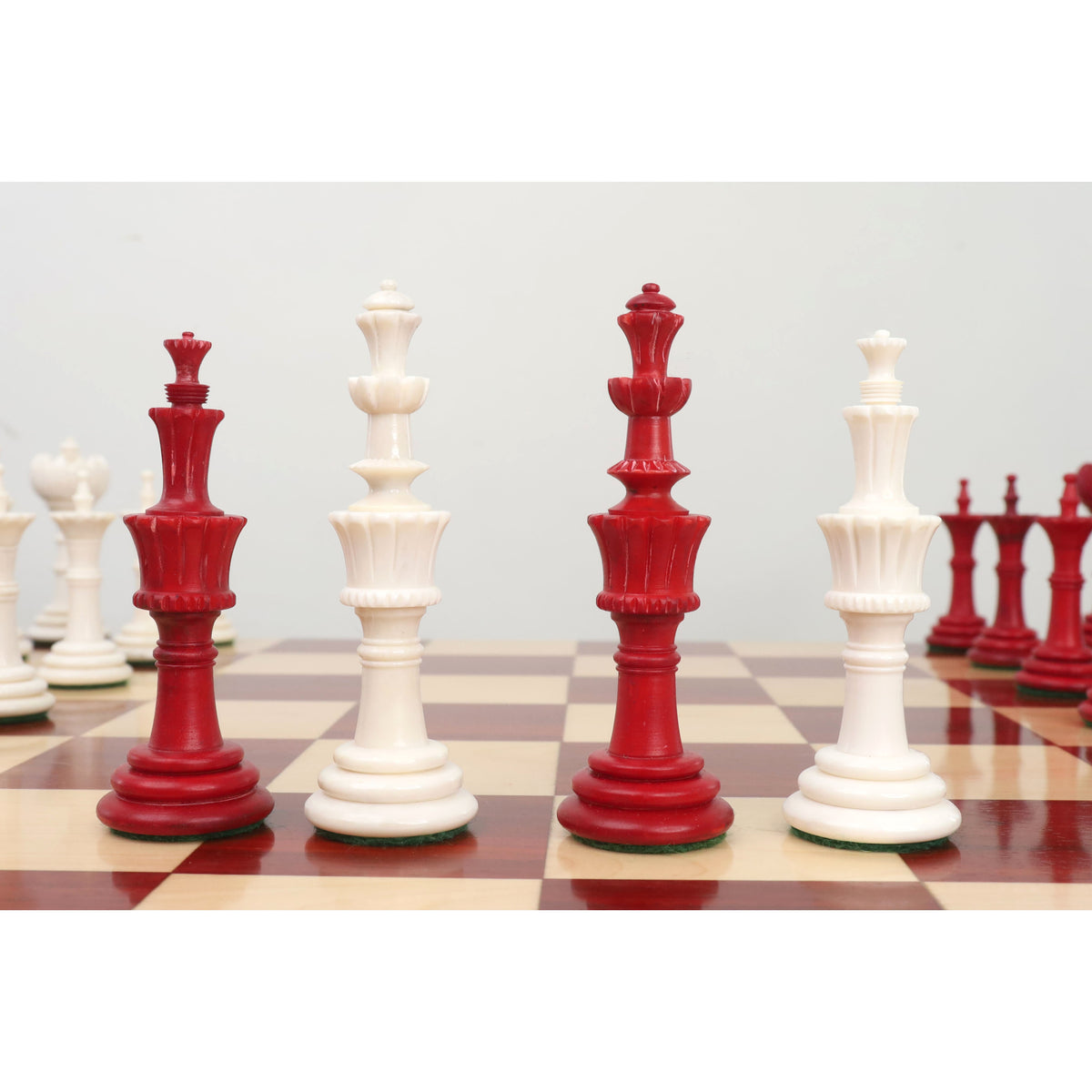 Four Turkish Tower pre-Staunton chess pieces in a row on a board.