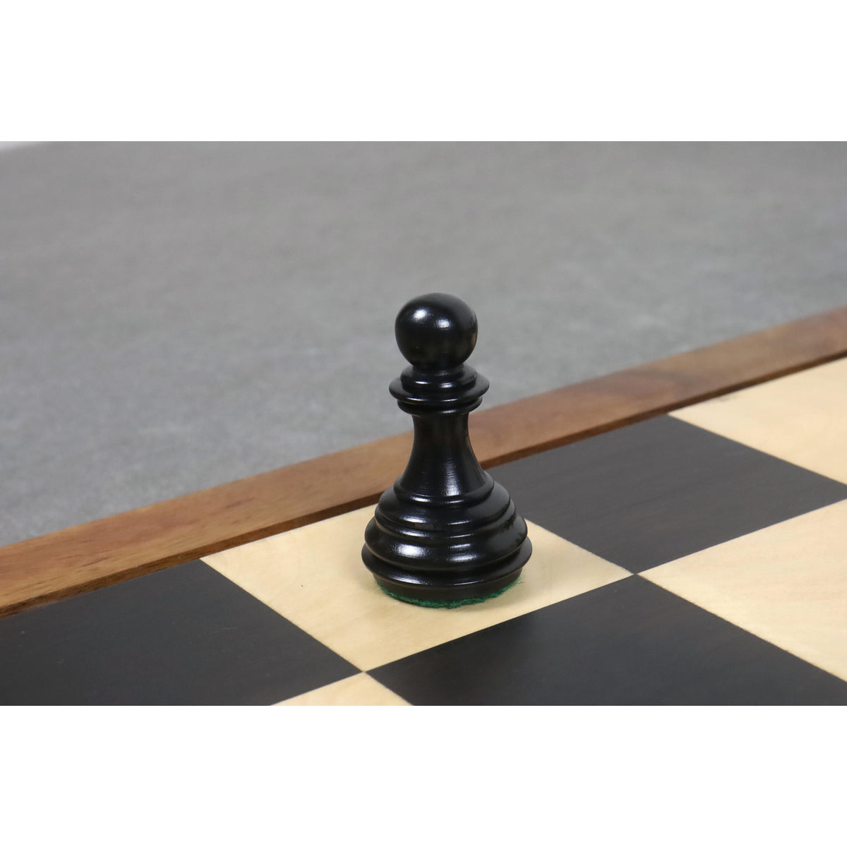 Close-up of a single dark wood pawn from the 3.8" Imperial Staunton ebony chess pieces set on a wooden board.