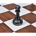 Single hand-carved black camel bone pawn chess piece on a wooden board.