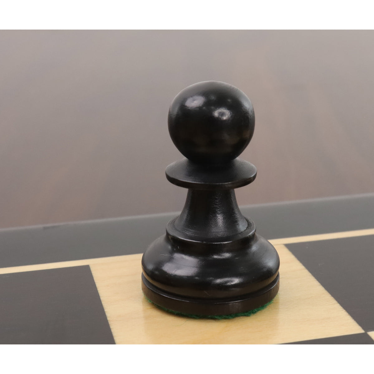 Close-up of a single ebonised boxwood bishop from the Reykjavik Series Staunton chess set on a board.