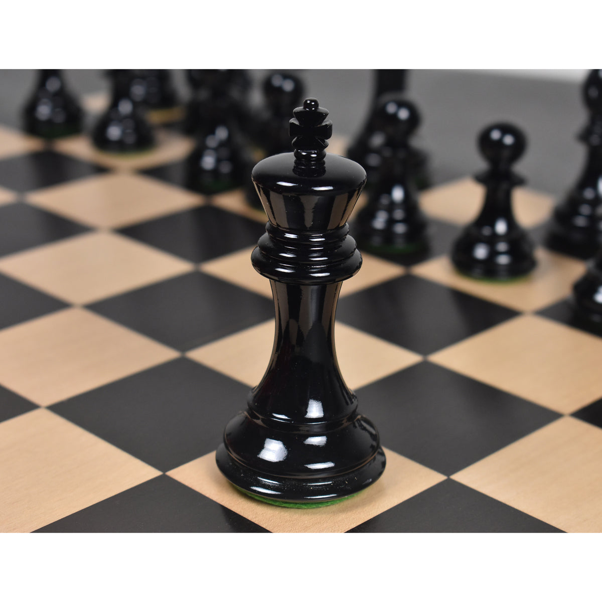 Black Staunton King piece centered on a wooden chessboard.
