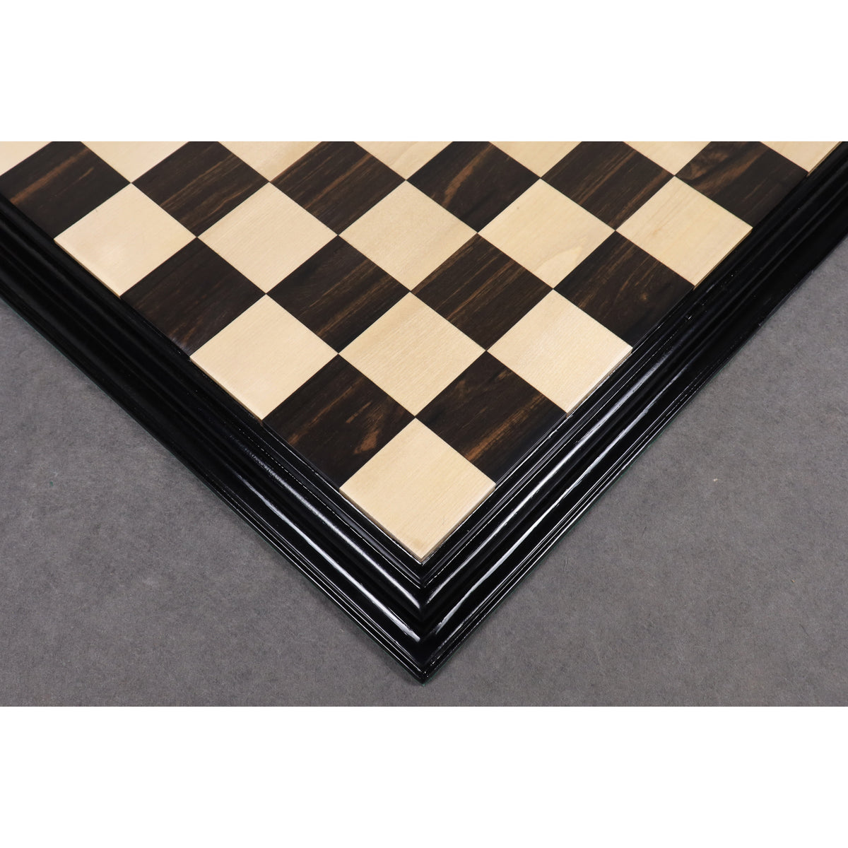 Corner view of a 21" ebony chess board showcasing the intricate carved border design.