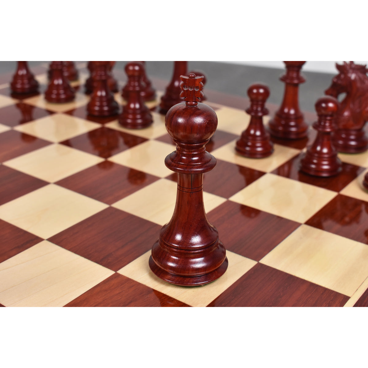 Dark bud rosewood Staunton king chess piece centerpiece on a wooden board.