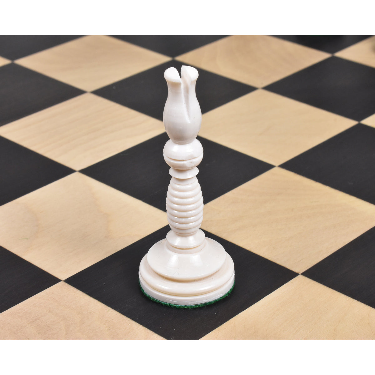 Ivory white camel bone bishop chess piece with hand-carved details on a checkered board.