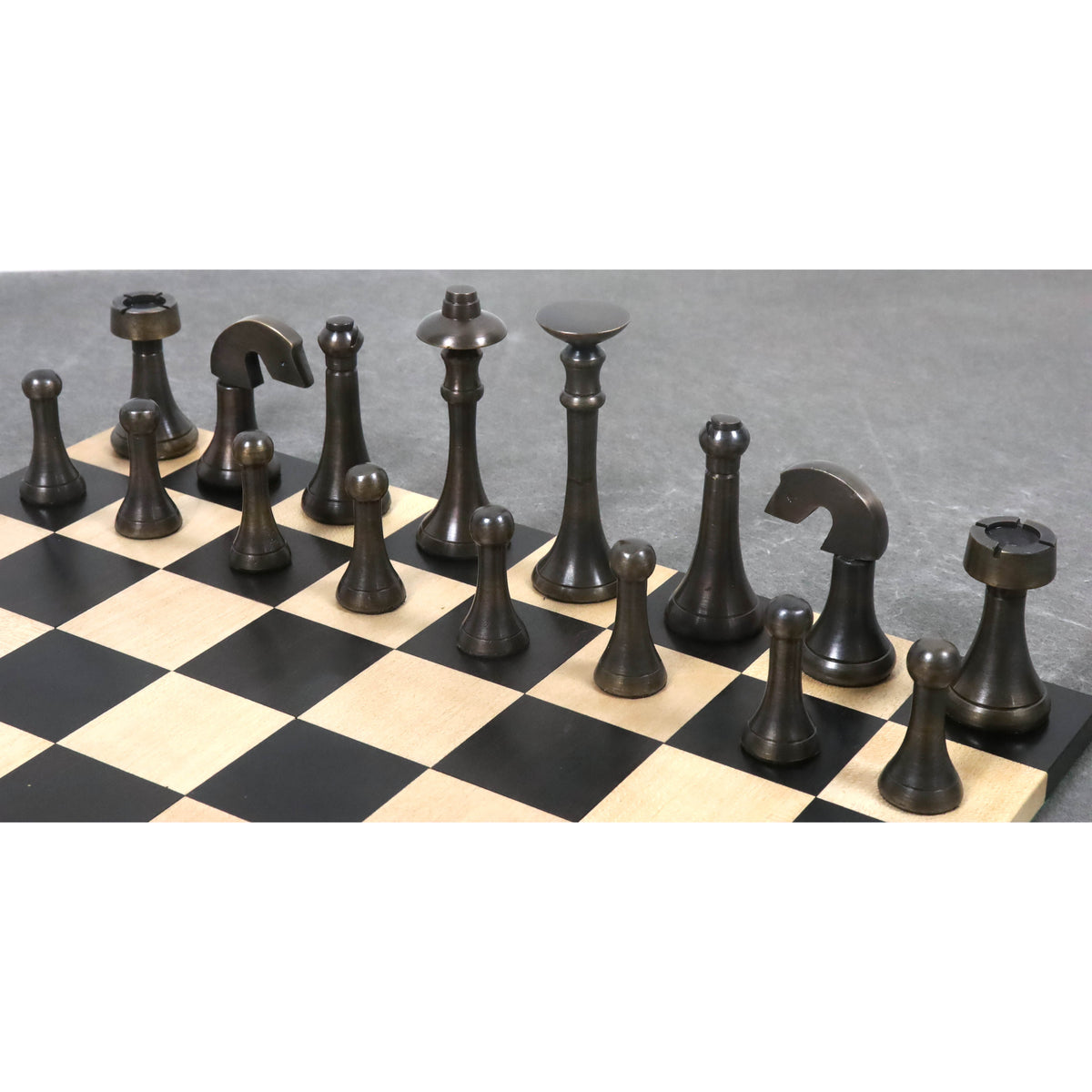 Antique brass luxury chess pieces arranged on a wooden board showing dark metal texture.