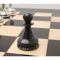 Minimalist close-up of a dark grey brass metal pawn piece from the luxury Staunton 1849 series.