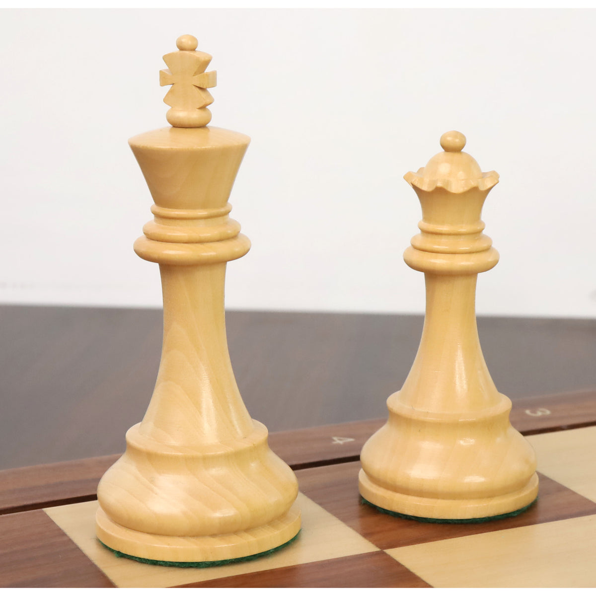 Finely crafted boxwood King and Queen from the classic Staunton chess set resting on a board.