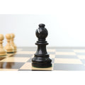 Sharp focus on a finely crafted ebonised boxwood bishop piece standing on a glossy chessboard.