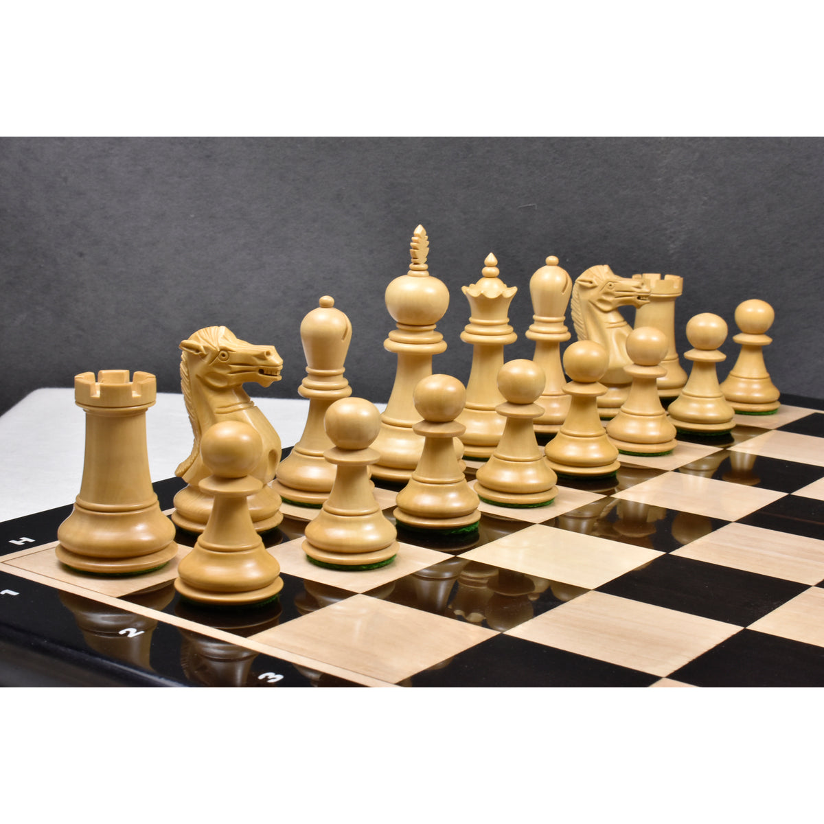 A set of light boxwood executive staunton pieces placed on a board.