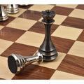 Antique brass queen and silver pawn with a felted base on a wooden chessboard.