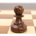 Close-up of a single golden rosewood pawn from the Reykjavik Series Staunton chess set on a board.