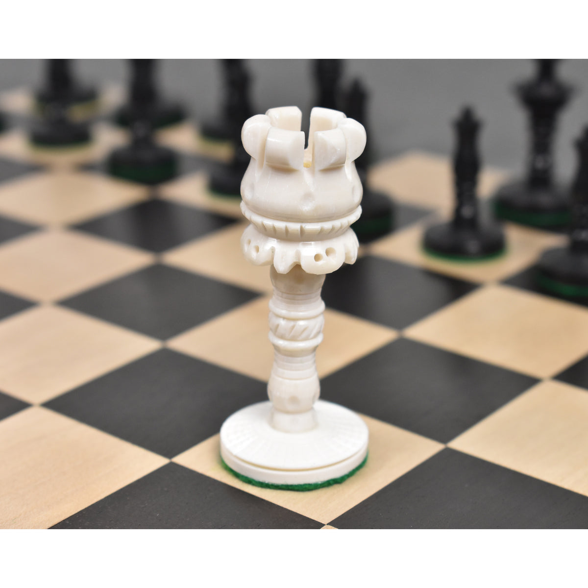 Close-up of the white camel bone Rook piece on a wooden chessboard.
