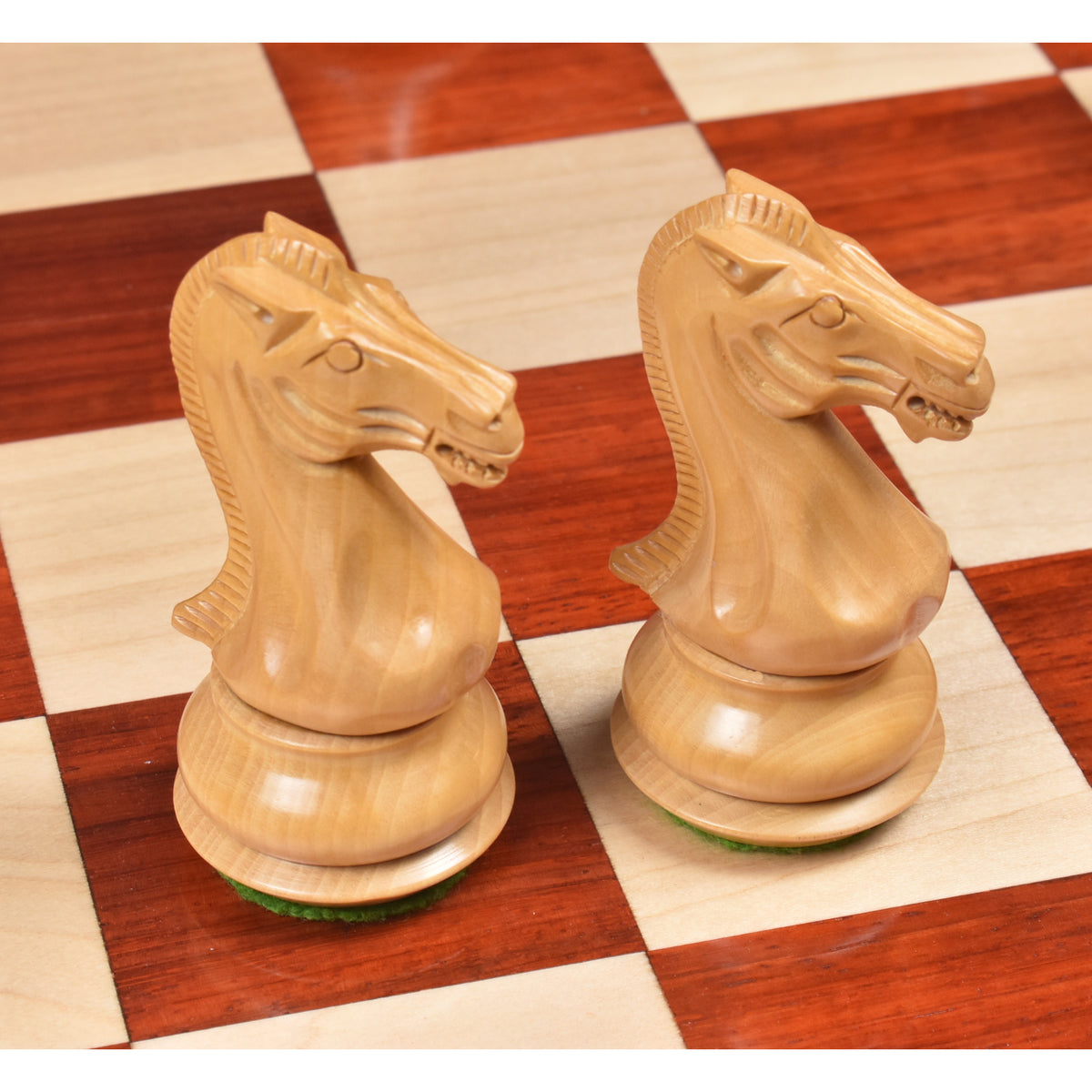 Close-up of two finely crafted Boxwood knights on a chessboard.