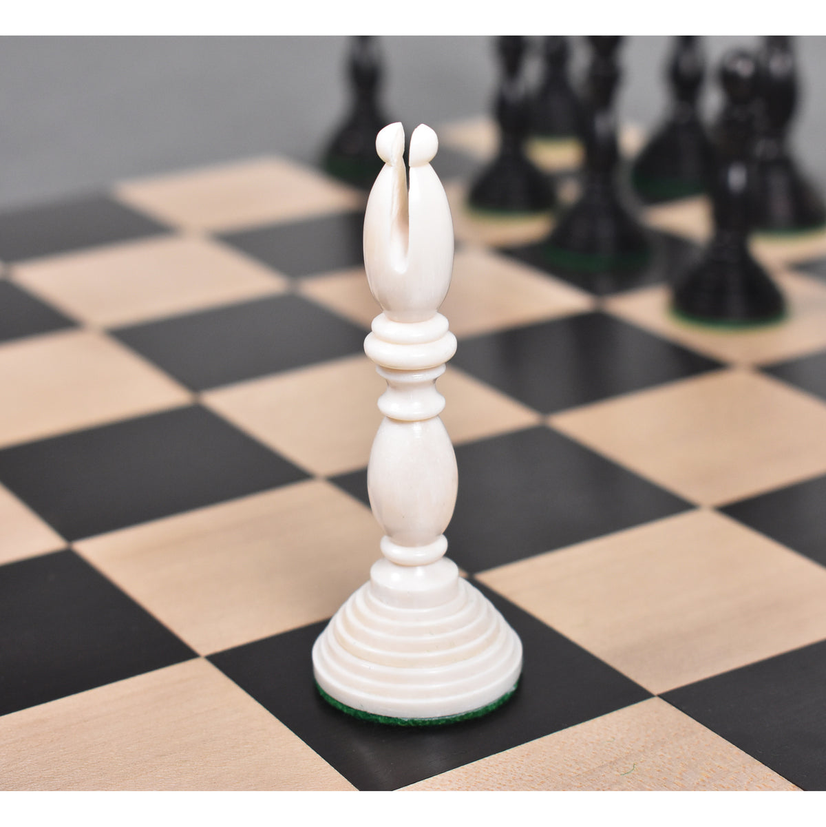 White antique pre-Staunton bishop chess piece on a wooden chessboard.