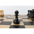 A lone black wooden Staunton pawn piece on a chessboard.