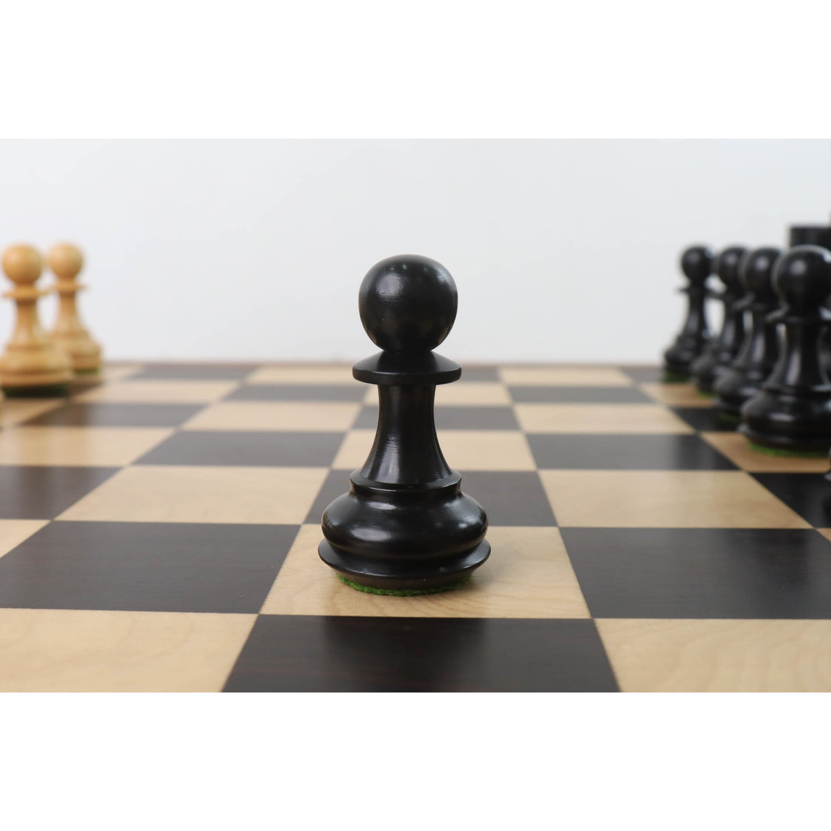 A lone black wooden Staunton pawn piece on a chessboard.