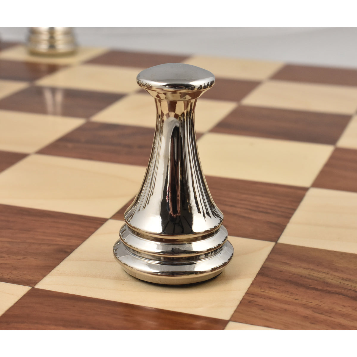 Polished silver metal pawn from the luxury Russian Zagreb set on a wooden chessboard.