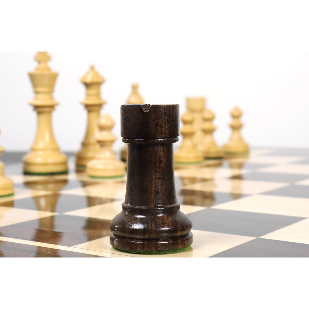Anjan rosewood Pinney Staunton rook chess piece close-up on a board with background pieces blurred.