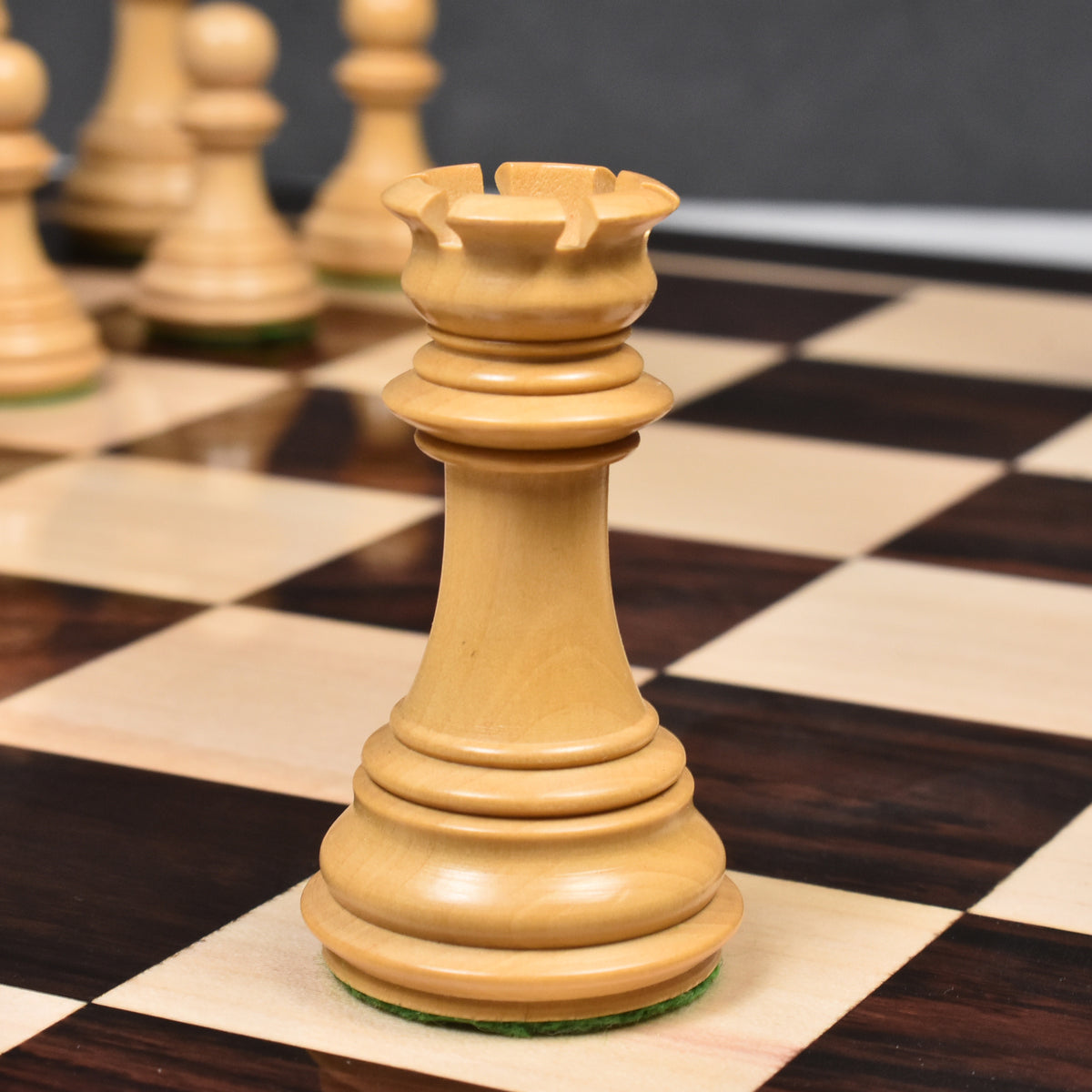 Close-up of a light boxwood Imperial Staunton rook standing on a glossy chessboard.