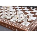 Hand-carved white camel bone chess pieces on an inlaid wooden board.
