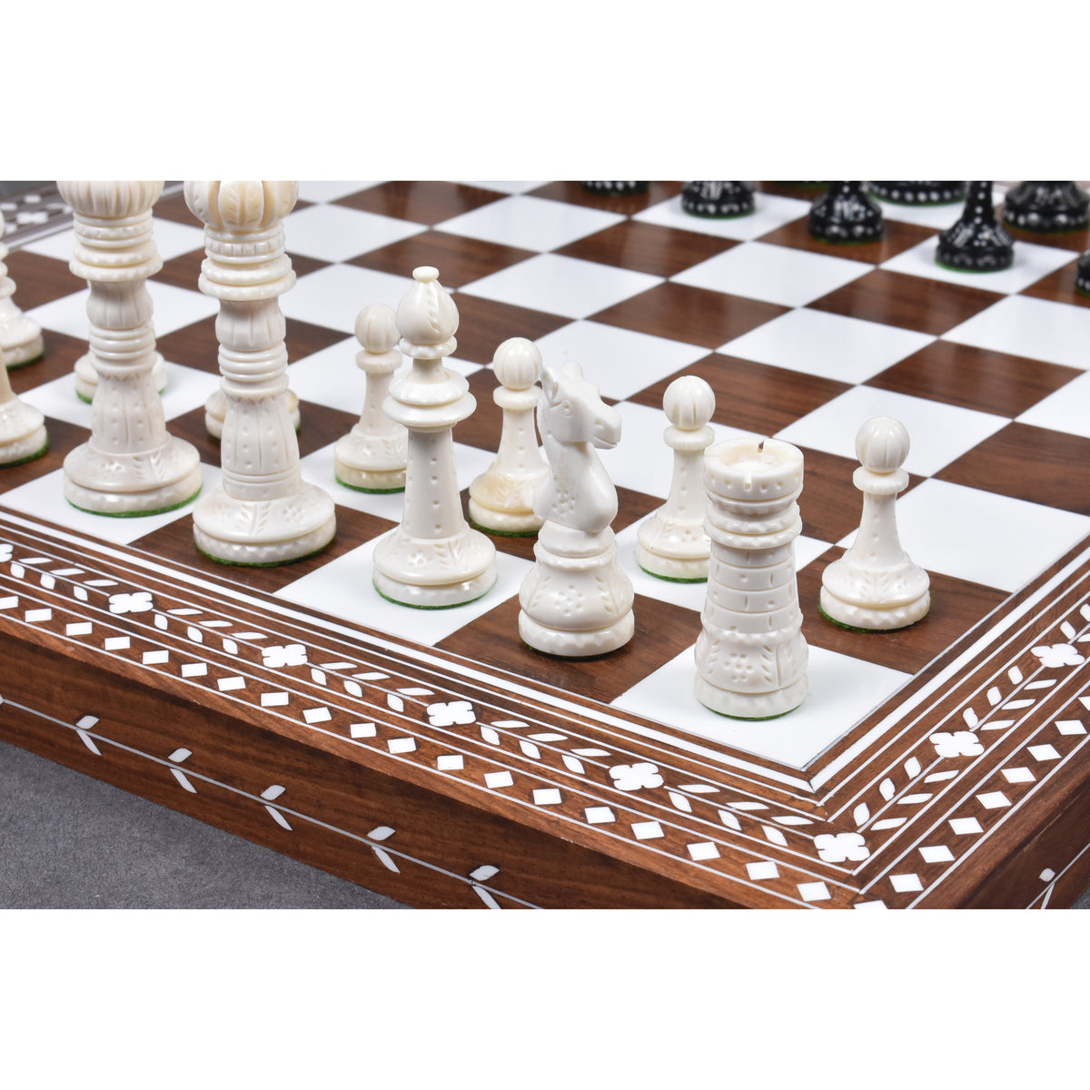 Hand-carved white camel bone chess pieces on an inlaid wooden board.
