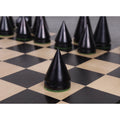 Conical ebonised boxwood Pawn piece from the Russian Poni minimalist collection on a chessboard.