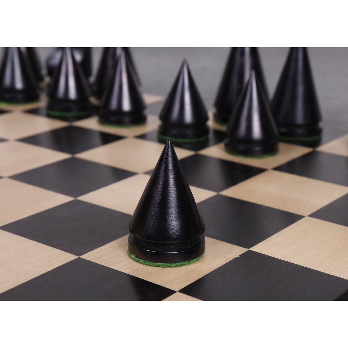 Conical ebonised boxwood Pawn piece from the Russian Poni minimalist collection on a chessboard.