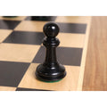 Single triple-weighted ebony pawn chess piece on a luxury wooden board.
