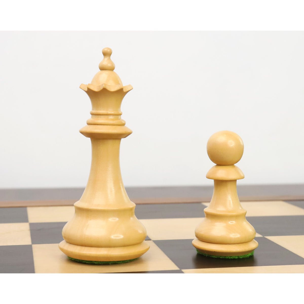 White queen and pawn from the 3.7" British Staunton chess set shown closely on a wooden board.