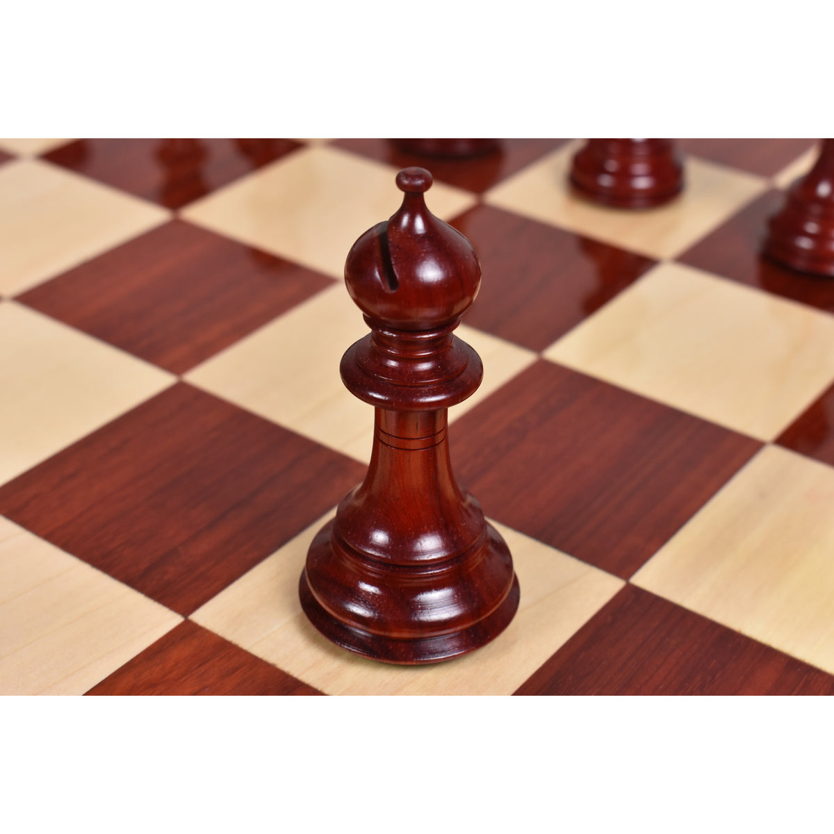 Detailed view of a hand-carved bud rosewood Staunton bishop chess piece on a board.