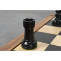A black ebonized boxwood W.T. Pinney Staunton rook featuring deep turret cuts on a chessboard.