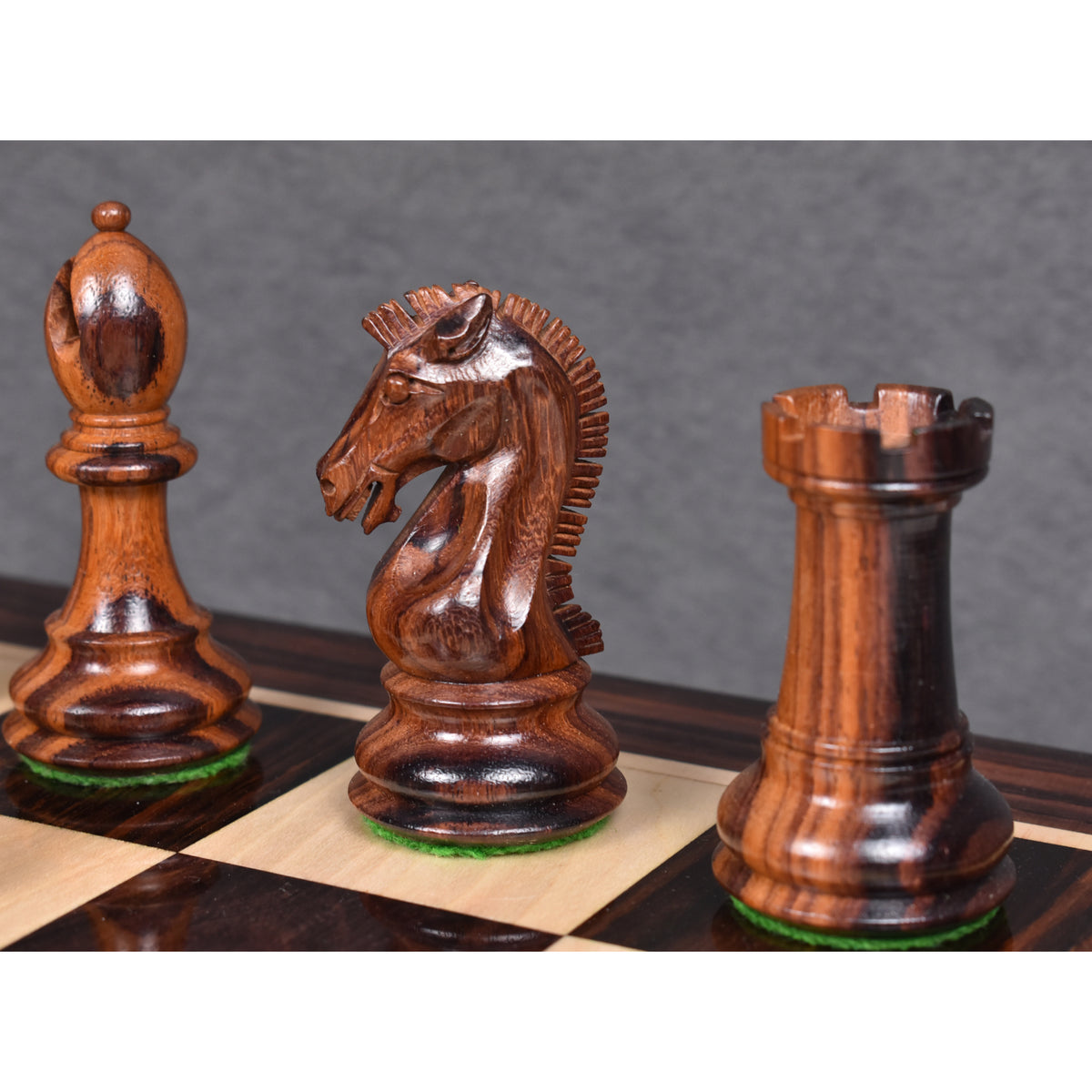 Dark rosewood bishop, knight, and rook from the 3.9" Craftsman Staunton chess set standing on a glossy board.