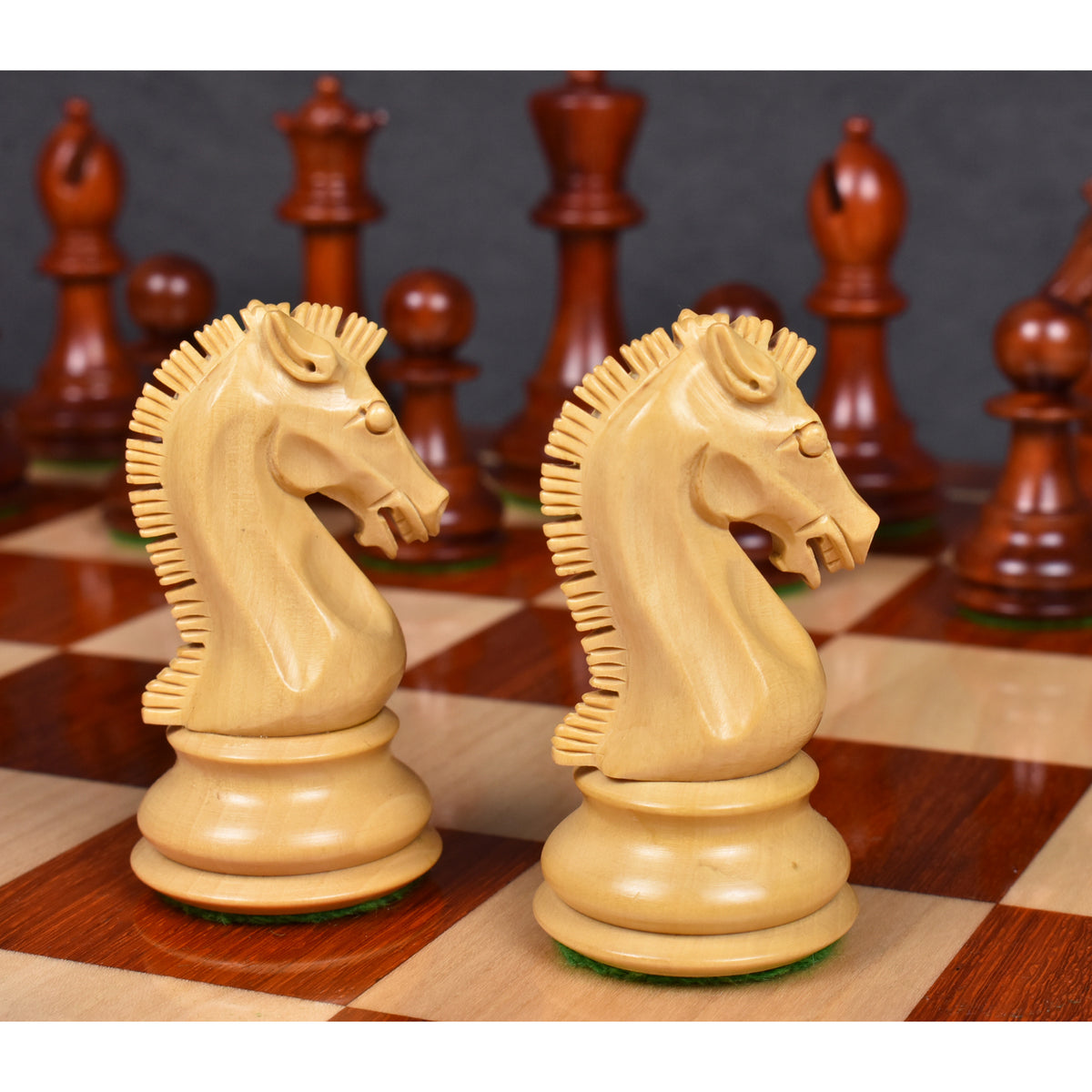 Two light Boxwood knights from the 3.9" Craftsman Staunton set face each other on a board with dark pieces behind them.