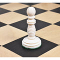 Single ivory white Minaret series hand-carved camel bone pawn piece on a wooden chess board.