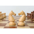 Two boxwood French Grandmaster knight pieces facing each other on a board.