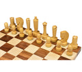 Side angle view of the complete natural boxwood side of Berliner modern minimalist chess pieces on a board.
