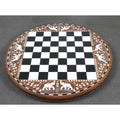 Top view of a round sheesham wood chess board featuring intricate white acrylic elephant and leaf engravings.
