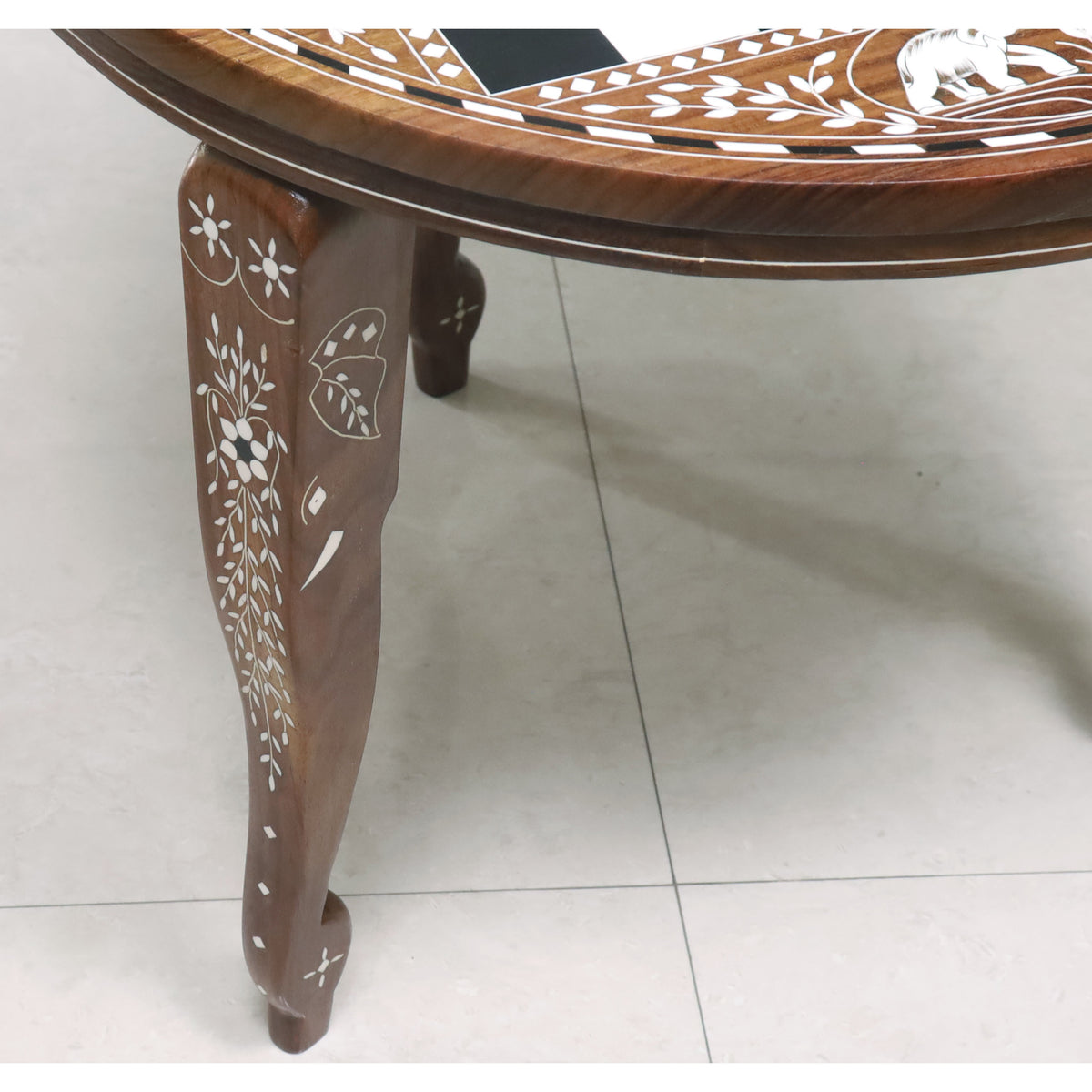 Detailed view of a hand-carved chess table leg featuring intricate white floral acrylic inlay patterns.