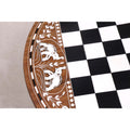 Intricate elephant engravings and geometric diamond inlays on the border of a rosewood chess table.