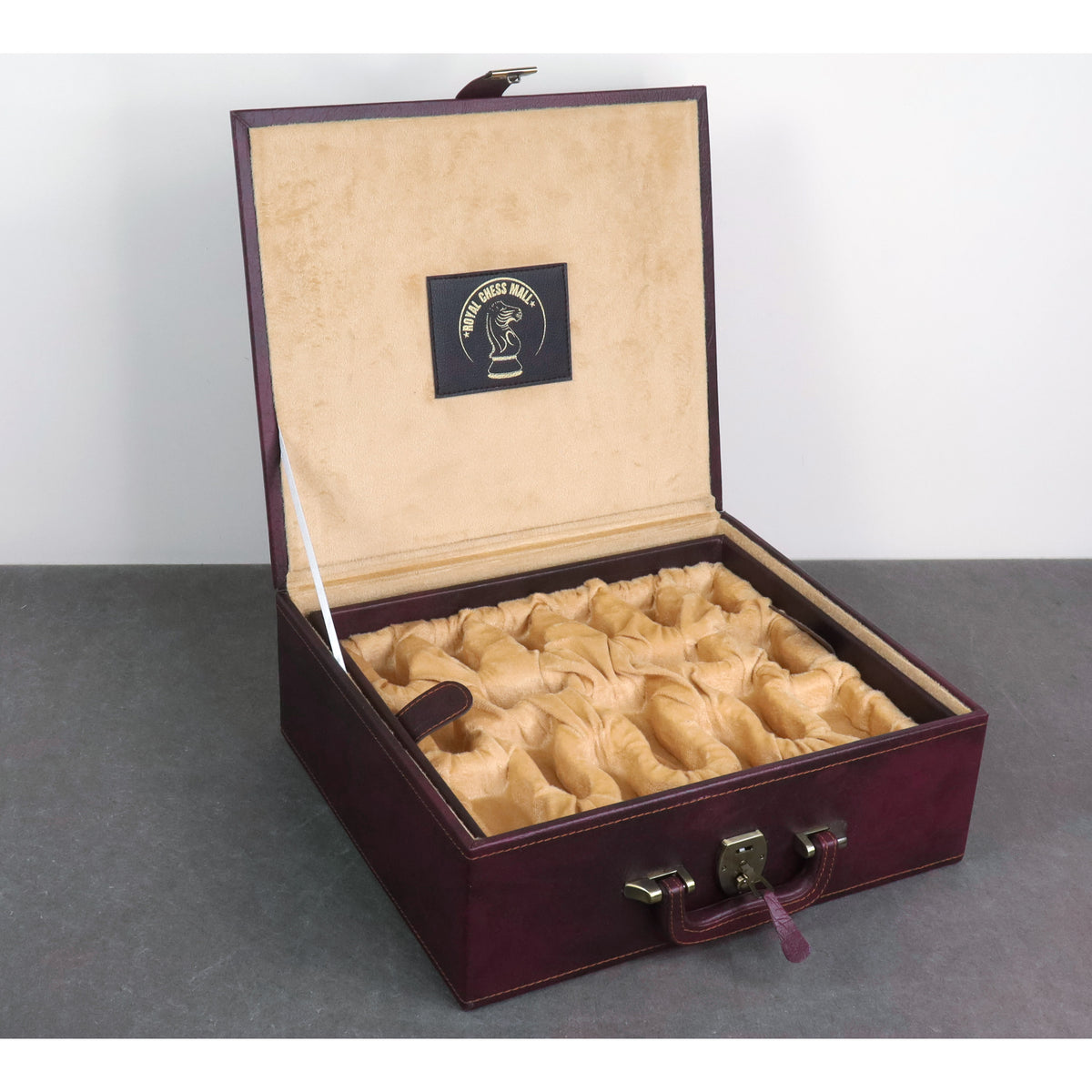 Open burgundy leatherette chess piece storage box with plush interior lining.