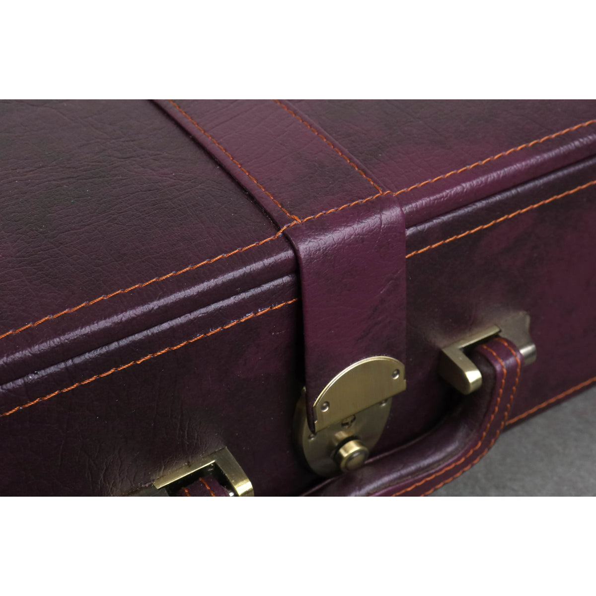 Macro shot of contrast stitching and brass accents on the burgundy chess coffer box.